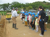 管理組合員が久保田保育所の園児達に苗植えの説明をしている様子の写真