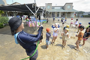 子供たちと水遊びをする石崎さんの画像