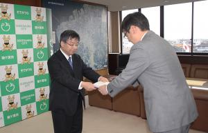 鎌田委員長より提言書を受領する市長