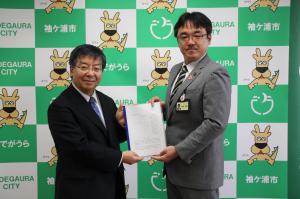 市長（右）に提言書を提出する鎌田委員長（左）