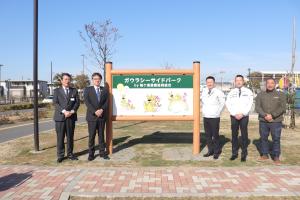 新しく設置された看板と造園協同組合の皆さんとの記念写真