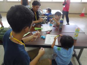 父親といっしょに紙とんぼを作る子どもの様子
