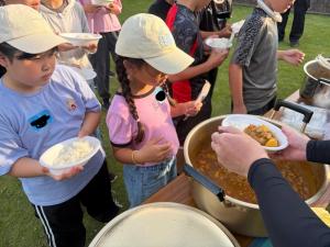カレーの配膳を受ける子供たちの写真